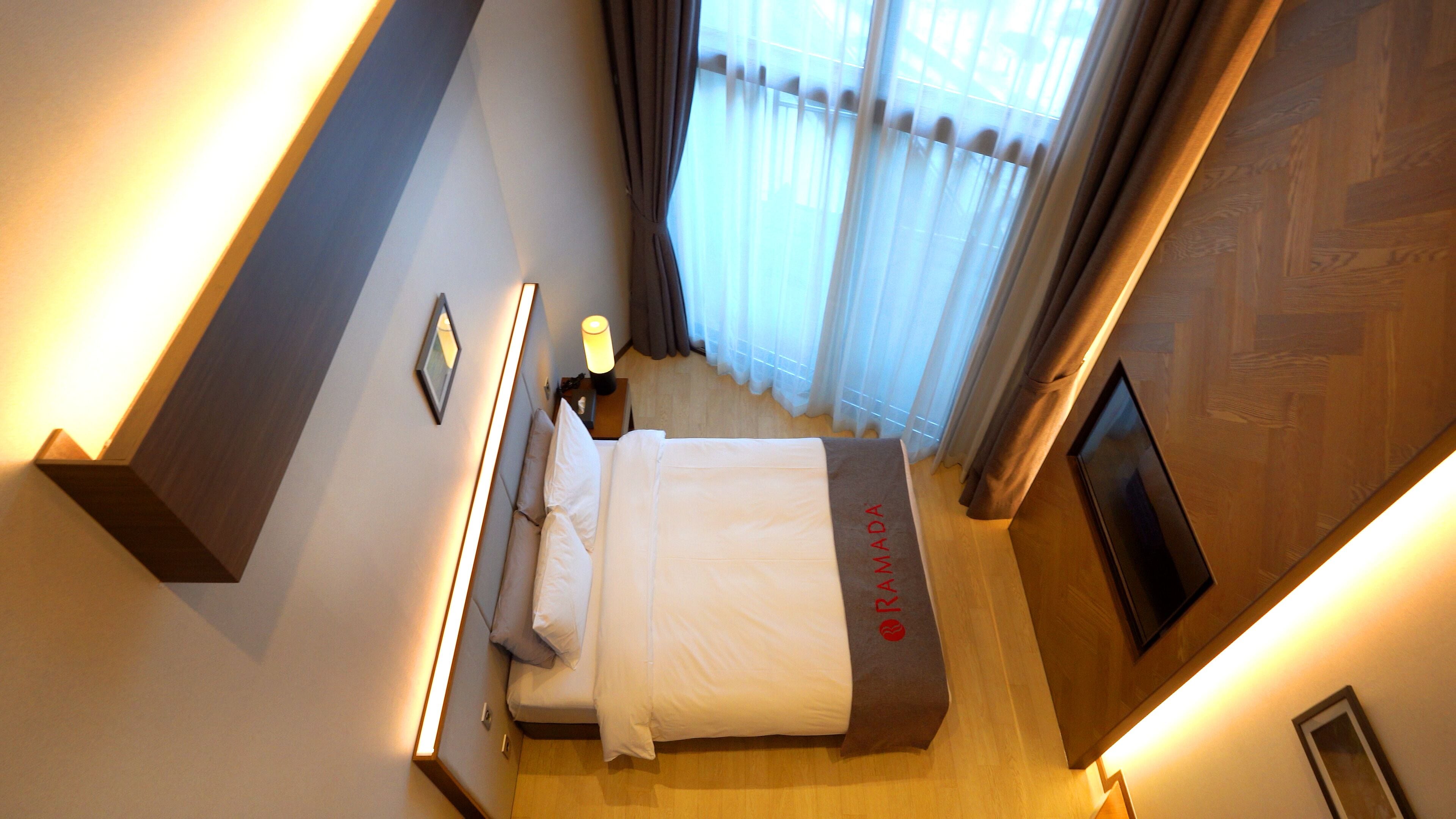Una habitación de hotel con una cama, una mesita de noche, una lámpara y un televisor.