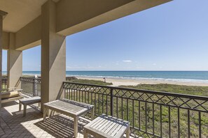 A balcony with a view of the beach and ocean.