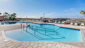 Une piscine avec un plongeoir, des chaises longues et une terrasse dallée.