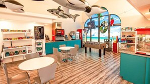 Un restaurante con piso de madera, una barra con máquina de Coca-Cola y una mesa de futbolín.