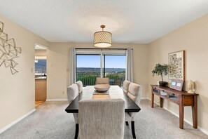 A dining area with a view of the landscape, a chandelier, and a table with chairs.