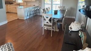 A spacious kitchen with white cabinets, a dining area with a large table and chairs, and a ceiling fan. - Canal/w dock, pool, ocean view, 1 block from beach & EV charger (Ocean Isle Beach)