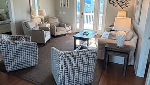 A living room with a ceiling fan, two armchairs, a sofa, a coffee table, and a side table. - Canal/w dock, pool, ocean view, 1 block from beach & EV charger (Ocean Isle Beach)