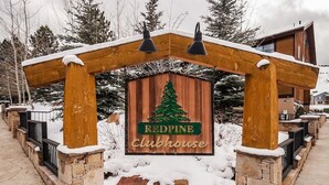Une arche en bois sur laquelle est accrochée une enseigne indiquant « Redpine Clubhouse », et un sapin de Noël.