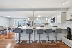 Une cuisine moderne dotée d’un grand îlot central, de tabourets de bar et d’un coin repas avec des chaises.