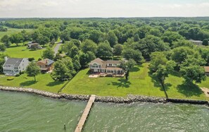 A waterfront property with multiple houses, a dock, and a stone wall. - Waterfront Home on the Chesapeake Bay with Pier only 30 min from naval academy (Stevensville)