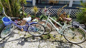 Two bicycles parked on a gravel path with a white fence and various plants in the background. - Cozy Cottage Goodland Fl.  (GOODLAND)
