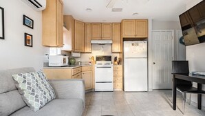 A compact kitchen with wooden cabinets, a white stove, and a refrigerator. - Cozy Cottage Goodland Fl.  (GOODLAND)