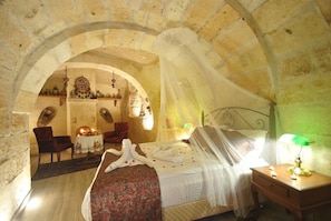 A room with a bed, a nightstand, a lamp, and an arched doorway leading to another room. - Hotel Elvan (Ürgüp)