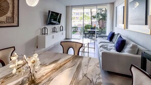 A modern living room with a marble dining table, a sofa, and a TV mounted on the wall.