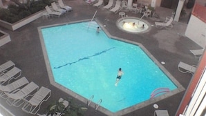 Une piscine avec des chaises longues et un espace équipé d’un jacuzzi.