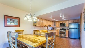 A spacious kitchen with wooden cabinets, a stainless steel refrigerator, and a dining area with a wooden table and chairs.