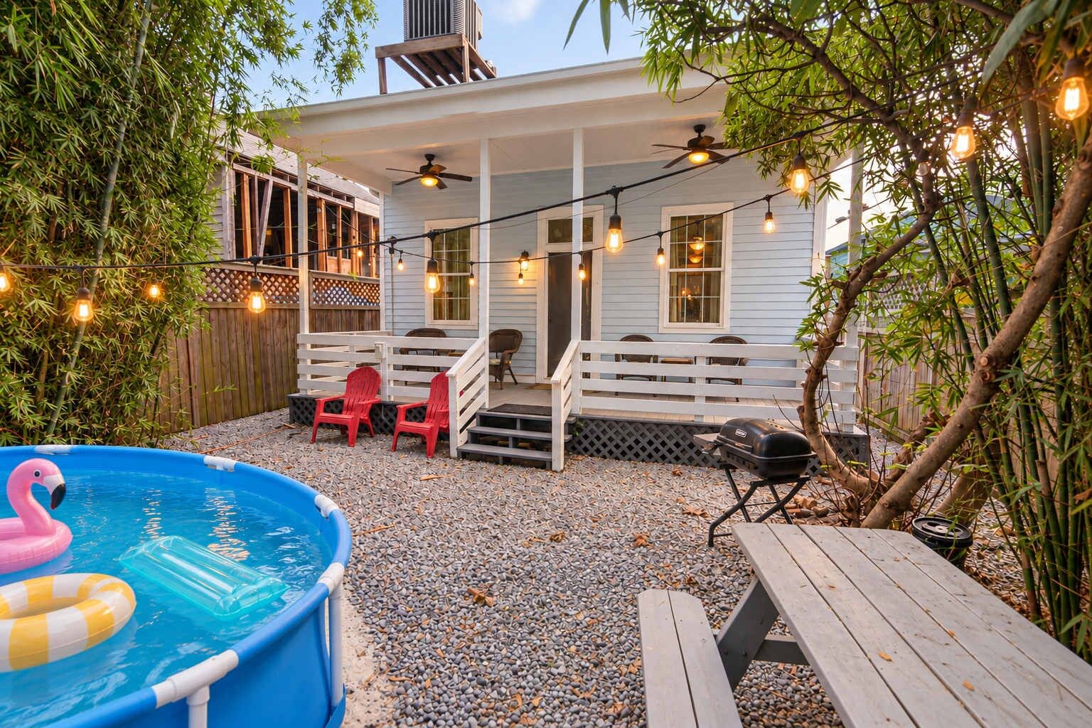 A backyard with a pool, outdoor seating, and string lights.