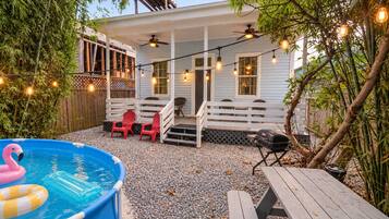 A backyard with a pool, outdoor seating, and string lights.