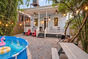 A backyard with a pool, outdoor seating, and string lights.