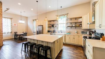 A spacious kitchen with a large island, wooden flooring, and pendant lighting.