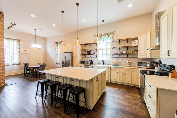 A spacious kitchen with a large island, wooden flooring, and pendant lighting.