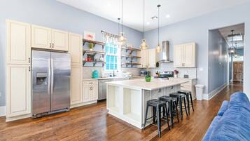 A modern kitchen with a central island, stainless steel appliances, and a blue accent wall.