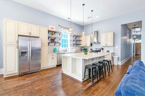 Une cuisine moderne dotée d’un îlot central, d’appareils électroménagers en acier inoxydable et d’un mur d’accent bleu.
