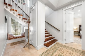 Stunning staircase leads to a comfortable seating area with a decorative trunk and patterned rug.
