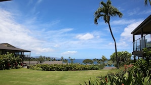 A well-maintained lawn, a tall palm tree, and a view of the ocean. - Wailea Elua #207 Ocean and Garden View Short Walk to the BEACH ..Not 14 Min (Wailea)