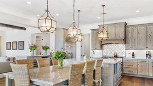 A spacious kitchen with a central island, wicker chairs, and pendant lighting. - Stay @ Sea Star on Isle of Palms (Isle of Palms)