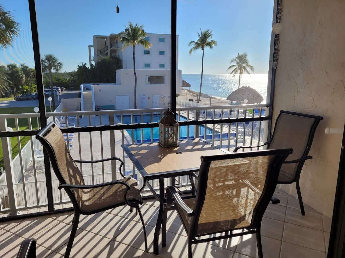 Ein Balkon mit Tisch und Stühlen mit Blick auf Strand und Pool.