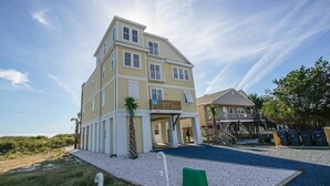 A multi-story building with a flat roof, a balcony, and a covered porch area. - "Sandy Dunes" - Oceanfront Home w/ Private Pool, 8 Bedrooms / 6.5 Bathrooms (Holden Beach)