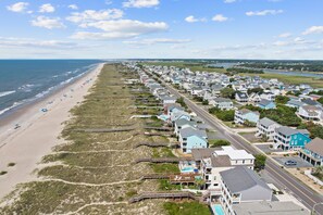 A coastal residential area with beachfront properties, a boardwalk, and a clear view of the ocean.