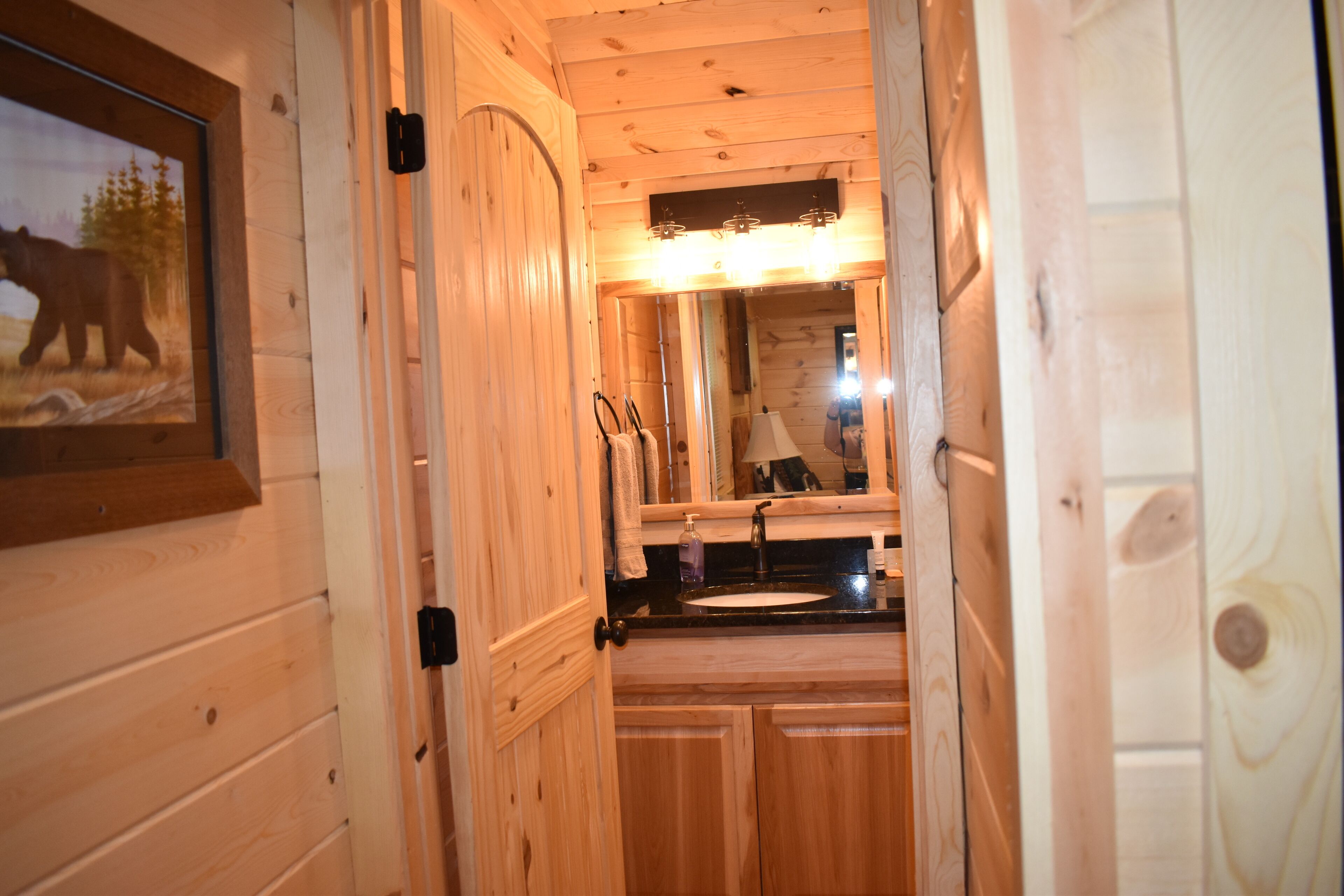 A wooden interior with a bathroom featuring a sink, mirror, and towel rack.