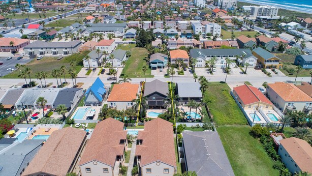 An aerial view of a coastal residential area with houses, a swimming pool, and a beach in the background. - Bahama Beach House • Private Heated Pool & Hot Tub • 3 Min Walk to Beach (South Padre Island)