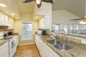 A kitchen with granite countertops, stainless steel sinks, and white cabinetry.