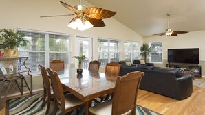 A spacious living area with a dining table, chairs, a sofa, and a television. - Bahama Beach House • Private Heated Pool & Hot Tub • 3 Min Walk to Beach (South Padre Island)