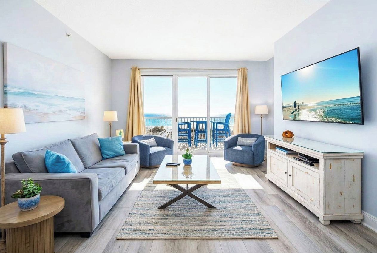 A modern living room with a sofa, armchairs, a coffee table, and a TV.