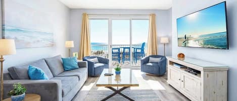 A modern living room with a sofa, armchairs, a coffee table, and a TV.
