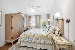 A bedroom with a bed, a wardrobe, a nightstand, a lamp, and a ceiling fan. - Immaculate Private Ocean Front Escape | Easy Walk To Beach | Private Pool (St. Simons Island)