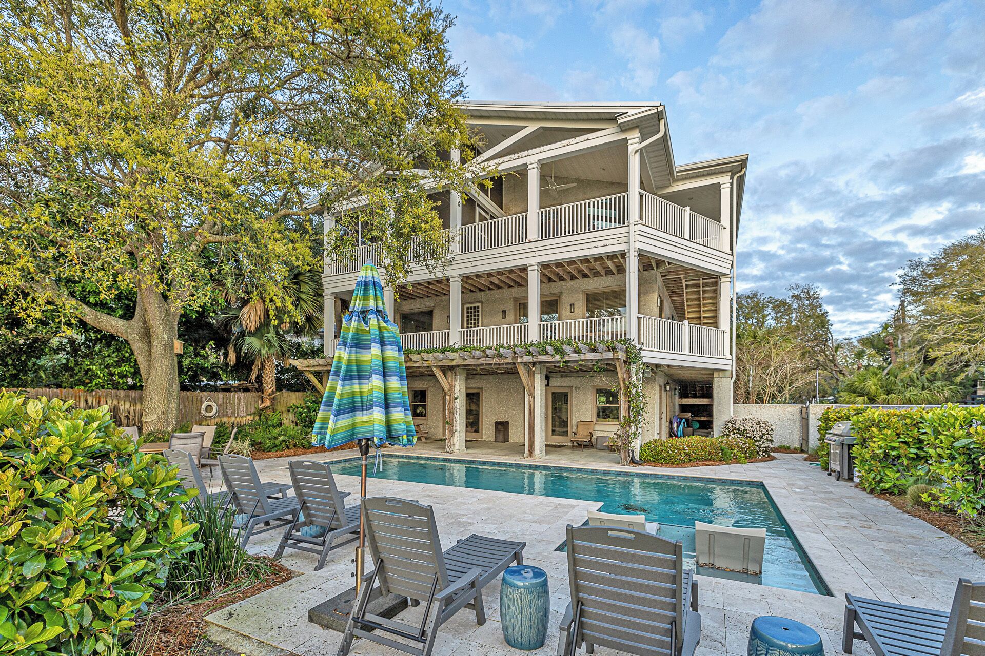 A two-story house with a pool, outdoor furniture, and a covered patio area.