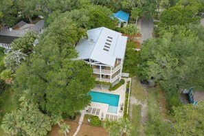 An aerial view of a two-story house with a swimming pool, surrounded by dense greenery. - Immaculate Private Ocean Front Escape | Easy Walk To Beach | Private Pool (St. Simons Island)