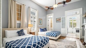 A hotel room with two beds, a ceiling fan, a large window, and a view of the outside.