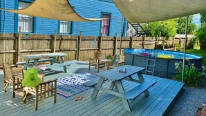 An outdoor patio with picnic tables, a hot tub, and a wooden deck.