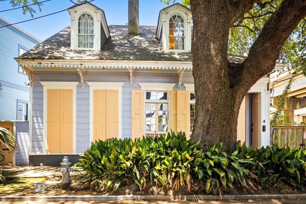 A two-story house with a large tree in front, a fire hydrant, and a well-maintained garden.