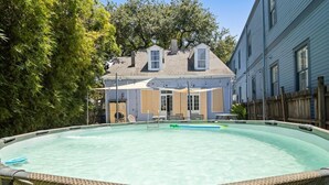 A swimming pool with a covered patio area and a house in the background.