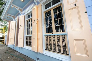 A building with pastel-colored exterior walls, large windows with decorative shutters, and a metal railing. - Historic Governor's Home w/ Pool, Near French Quarter (New Orleans)