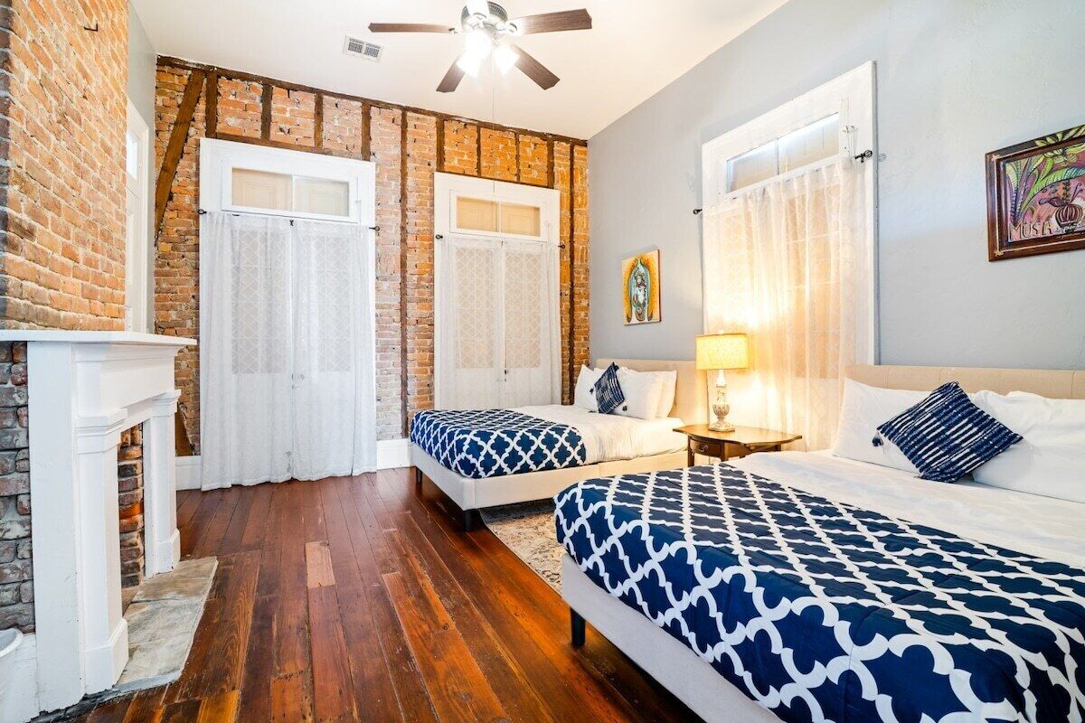 A room with two beds, a fireplace, and a ceiling fan.