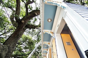 Un edificio con una facciata blu, un albero di fronte e una porta gialla.