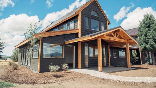 A two-story log cabin with a large porch and multiple windows. - Teton View - Cache Vista Ranch Estate - Sleeps 32 (Tetonia)