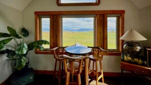 A room with a table and chairs facing a large window with a view of mountains. - Teton View - Cache Vista Ranch Estate - Sleeps 32 (Tetonia)