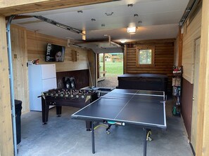Un garage équipé d’un baby-foot, d’une table de ping-pong et d’un réfrigérateur.