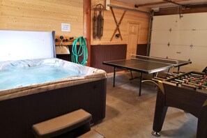 Een kamer met een jacuzzi, een tafeltennistafel en een tafelvoetbaltafel.
