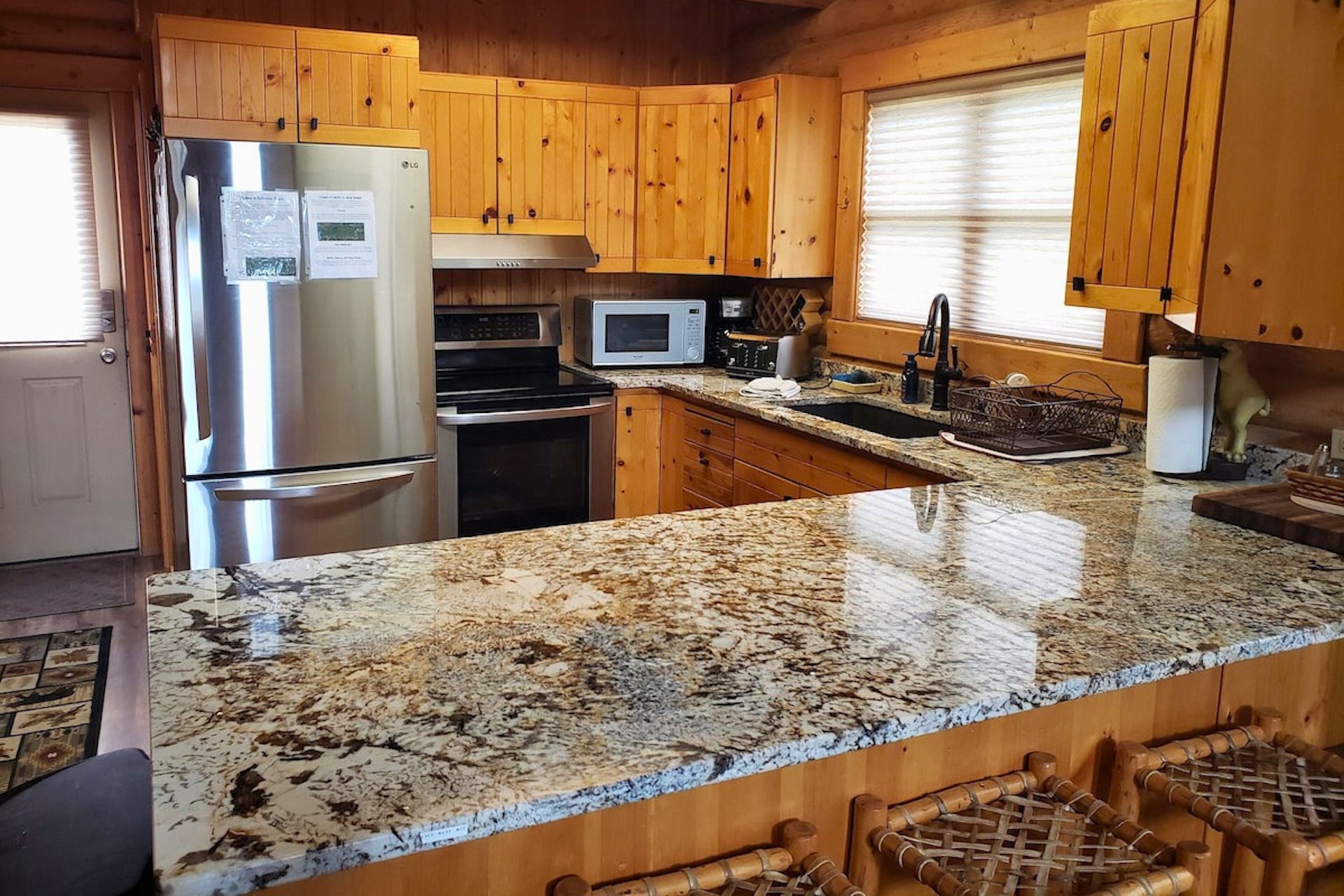 A kitchen with wooden cabinets, stainless steel appliances, granite countertops, and a built-in sink.